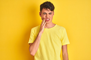 Wall Mural - Teenager boy wearing yellow t-shirt over isolated background touching mouth with hand with painful expression because of toothache or dental illness on teeth. Dentist concept.