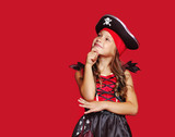 Pretty pirate girl looking to the copy space area against red background