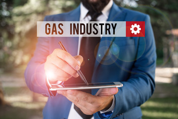 Text sign showing Gas Industry. Business photo showcasing global processes exploration and selling of petroleum products Businessman in blue suite stands with mobile phone in hands