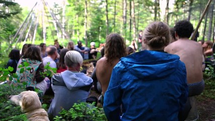 Wall Mural - Diverse people enjoy spiritual gathering A curious dog turns head to the side as a multiethnic group of people celebrate freedom and spirituality together in a woodland campsite, short slow-mo video.