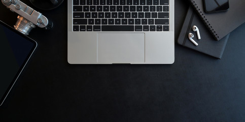 Sticker - top view of dark modern workplace with open laptop computer and office supplies on black leather des