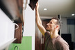 © DragonImages - Young man opening kitchen cabinet to take out plate and cup for the dinner