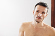 © DragonImages - Handsome young man with beautiful skin looking at mirror after taking shower in bathroom