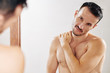 © DragonImages - Shirtless fit man touching shoulder when looking a himself in morror after taking shower