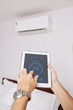 © DragonImages - Hands of man using climate control application on tablet computer to regulate temperature in his room