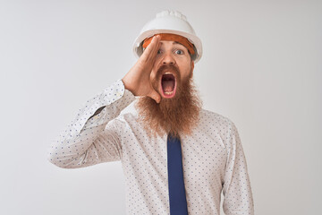 Sticker - Young redhead irish architect man wearing security helmet over isolated white background shouting and screaming loud to side with hand on mouth. Communication concept.