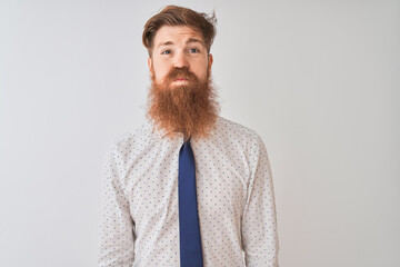 Sticker - Young redhead irish businessman standing over isolated white background puffing cheeks with funny face. Mouth inflated with air, crazy expression.