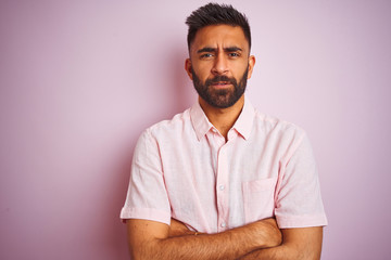 Wall Mural - Young indian man wearing casual shirt standing over isolated pink background skeptic and nervous, disapproving expression on face with crossed arms. Negative person.