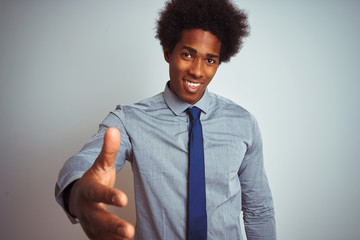 Sticker - American business man with afro hair wearing shirt and tie over isolated white background smiling friendly offering handshake as greeting and welcoming. Successful business.