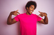 © Krakenimages.com - Young american man with afro hair wearing t-shirt standing over isolated pink background looking confident with smile on face, pointing oneself with fingers proud and happy.