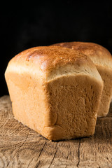 Two loaves of white bread on an oak board