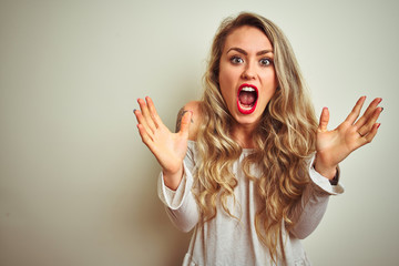 Canvas Print - Young beautiful woman standing over white isolated background celebrating crazy and amazed for success with arms raised and open eyes screaming excited. Winner concept