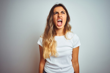 Sticker - Young beautiful woman wearing casual white t-shirt over isolated background angry and mad screaming frustrated and furious, shouting with anger. Rage and aggressive concept.