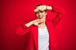 © Krakenimages.com - Young beautiful business woman standing over red isolated background Smiling cheerful playing peek a boo with hands showing face. Surprised and exited