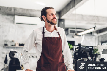 Portrait of handsome bearded barista man small business owner working behind the counter bar in a cafe