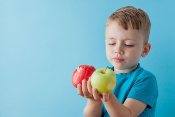 Wall Mural - Little Boy Holding an Apples in his hands on blue background, diet and exercise for good health concept