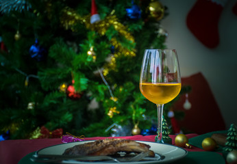 wine glass placed on a table with food for celebrate.with a backdrop of Christmas trees.