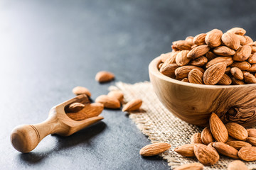 Almonds on dark stone table. Fresh peeled almonds in bowl. Almonds in scoop.