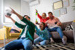 © Zoran Zeremski - Group of cheerful friends watching soccer match and celebrating victory at home. Man on his knees cheering for his team.