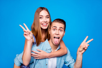 Wall Mural - Close-up portrait of two nice attractive crazy foolish cheerful cheery glad positive people piggy-backing showing v-sign having fun fooling isolated on bright vivid shine vibrant blue color background