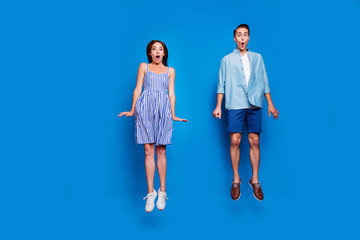 Wall Mural - Full length body size view of two nice attractive funky comic childish cheerful cheery amazed people jumping having fun isolated on bright vivid shine vibrant blue color background