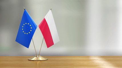 Wall Mural - European Union and Polish flag pair on a desk over defocused background 