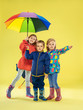 © master1305 - A full length portrait of a bright fashionable kids in a raincoat and umbrella of rainbow colors on yellow studio background. Autumn and spring fashion for kids. Cute stylish girls and boy. Having fun
