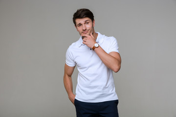 Poster - Image of young brunette man looking at camera and touching his chin