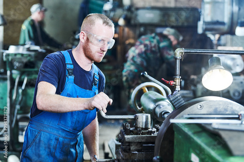 Fotografía worker turner operating lathe machine at industrial manufacturing factory