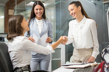 Wall Mural - Young business women shaking hands in office