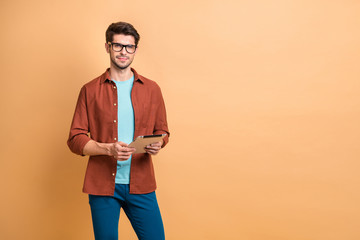 Poster - Portrait of his he nice attractive calm peaceful successful content brunet guy consultant holding in hands digital ebook browsing web isolated over beige color pastel background