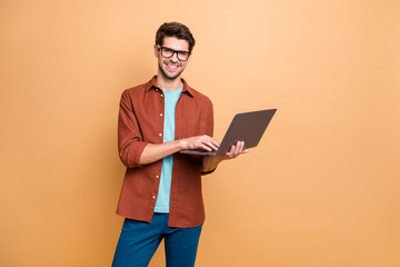 Fototapete - Portrait of his he nice attractive cheerful cheery successful content smart clever brunet guy agent broker holding in hands laptop working isolated over beige color pastel background