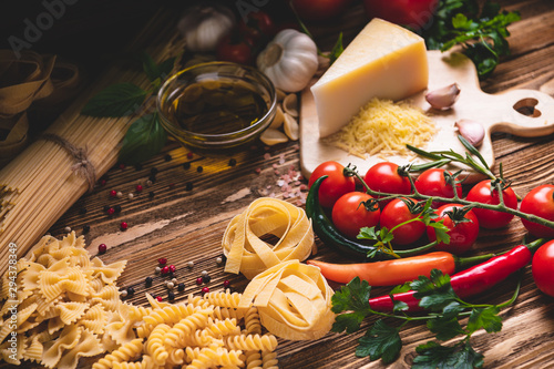 Fotomural Tasty appetizing italian spaghetti pasta ingredients for kitchen cuisine with tomato, cheese parmesan, olive oil, fettuccine and basil on wooden brown table