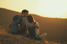Young Happy Couple Is Hiking In Mountain And Enjoying Sunset.