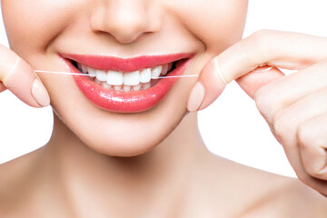 Young beautiful woman is engaged in cleaning teeth. Beautiful smile healthy white teeth. A girl holds a dental floss. The concept of oral hygiene.