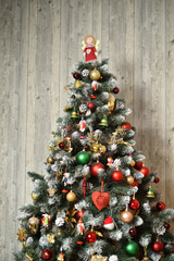 beautiful decorated christmas tree on a background of a wooden wall. top of christmas tree