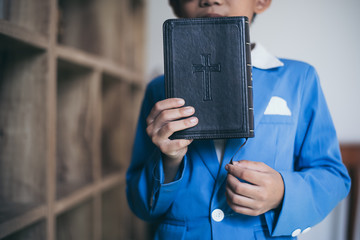 Little Asian boy pray with bible in classroom at school, bible study concept