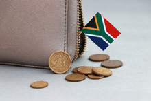Heap Of South African Rand Coin Money And Mini South African Flag Stick On The Leather Wallet On Grey Background.