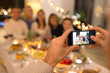 © Syda Productions - celebration, holidays and people concept - man with smartphone taking picture of family at dinner party