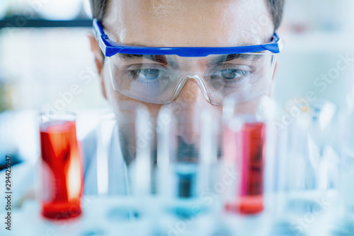 Cuadros en Lienzo Close up scientist wear protective eye glasses looking at medical test in glass