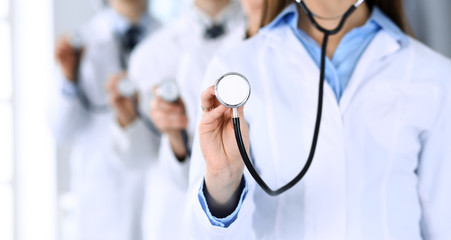 Wall Mural - Group of doctors holding stethoscope head close-up. Physicians ready to examine and help patient. Medical help, insurance in health care, best treatment and medicine concept