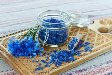 Blue cornflower or centaurea flower tea is good as diuretic, in cosmetics and eyewash, fresh blossom and a jar with dry petals nearby, closeup, copy space, herbal drinks concept