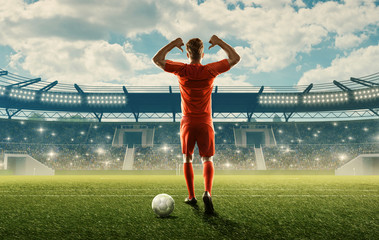 Wall Mural - Professional soccer player in sports uniform with a ball on a field with tribunes, green grass and spectators. Blue cloudy sky