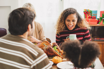 Happy Thanksgiving dinner party with family and food with turkey on table