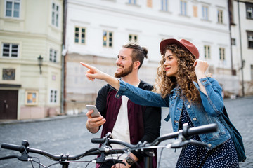 Wall Mural - young tourist couple travellers with smartphone and electric scooters in town.