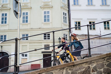 Wall Mural - young tourist couple travellers with electric scooters in small town.