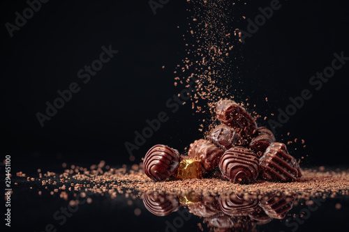Fotomural Chocolate candies on a black background sprinkled with chocolate chips