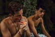 © Westend61 - Two bare chested friends smoking a joint of marijuana in nature