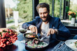 © Тарас Нагирняк - Successful man holding a knife and a fork ready to eat a beef steak in restaurant terrace.