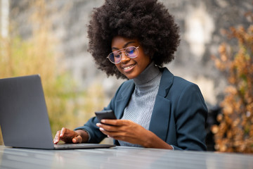 young african american business woman smiling with with laptop and mobile phone